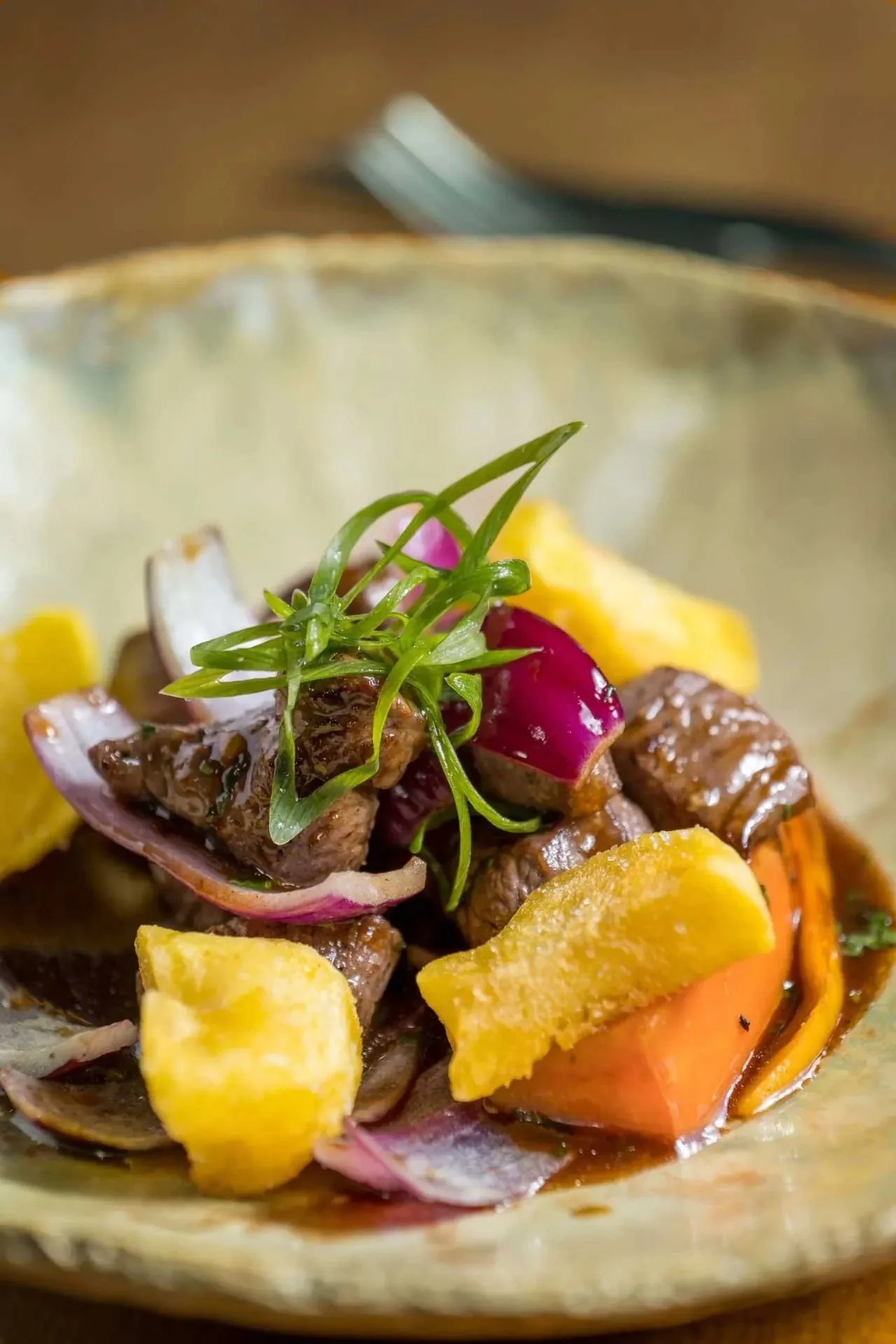Pieces of beef with diced yellow potato and herbs on a rustic plate