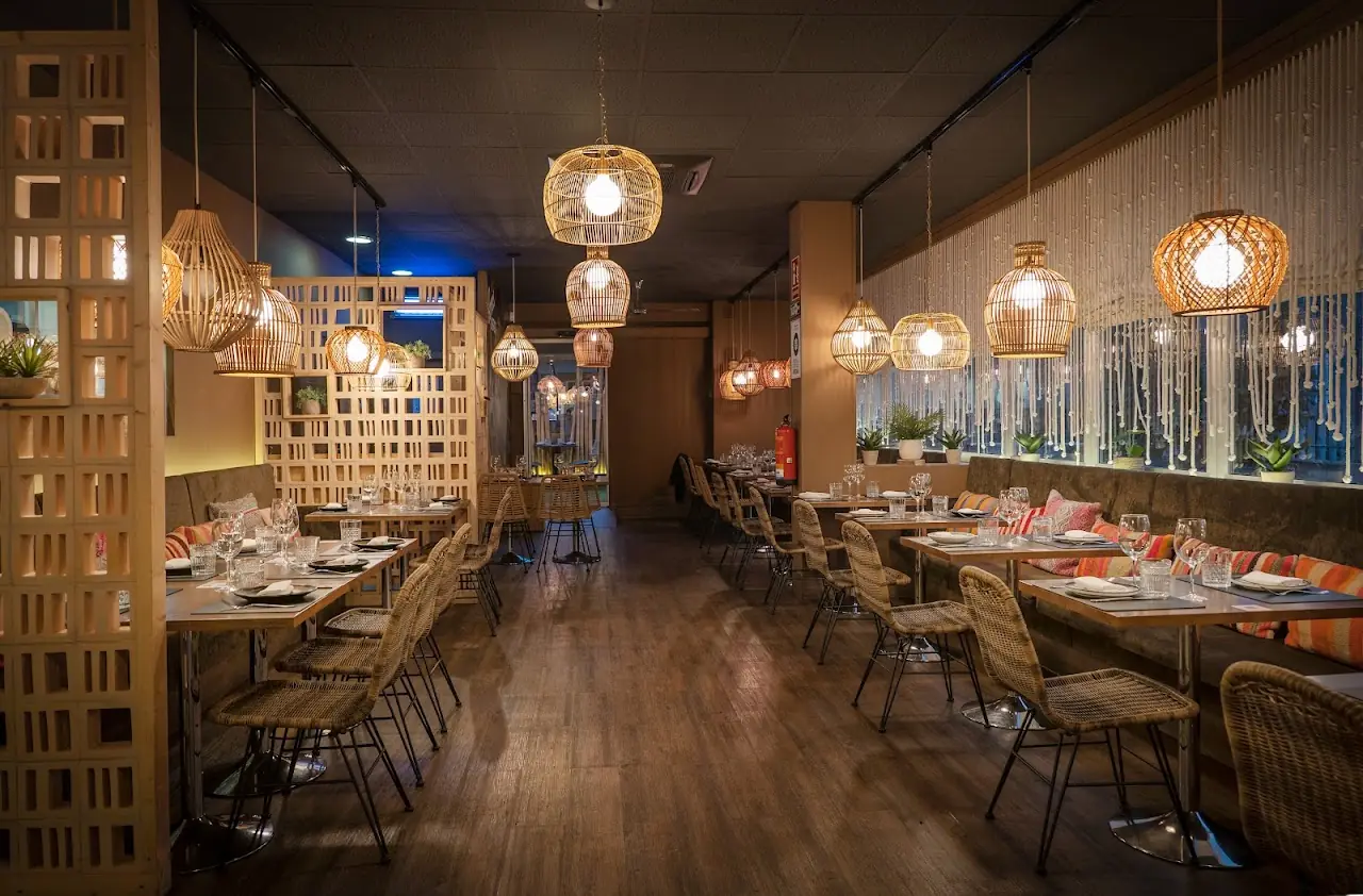 Dining room with wooden tables, woven pendant lights, and a slatted wood partition.