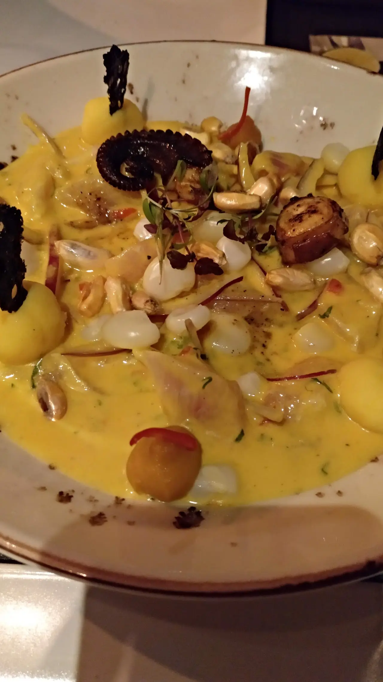 Seafood in a creamy yellow sauce with mussels, corn, and herbs.