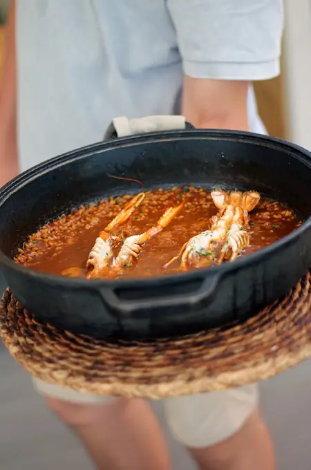 Seafood rice with whole prawns and langoustine in a black paella pan at Camping Mar