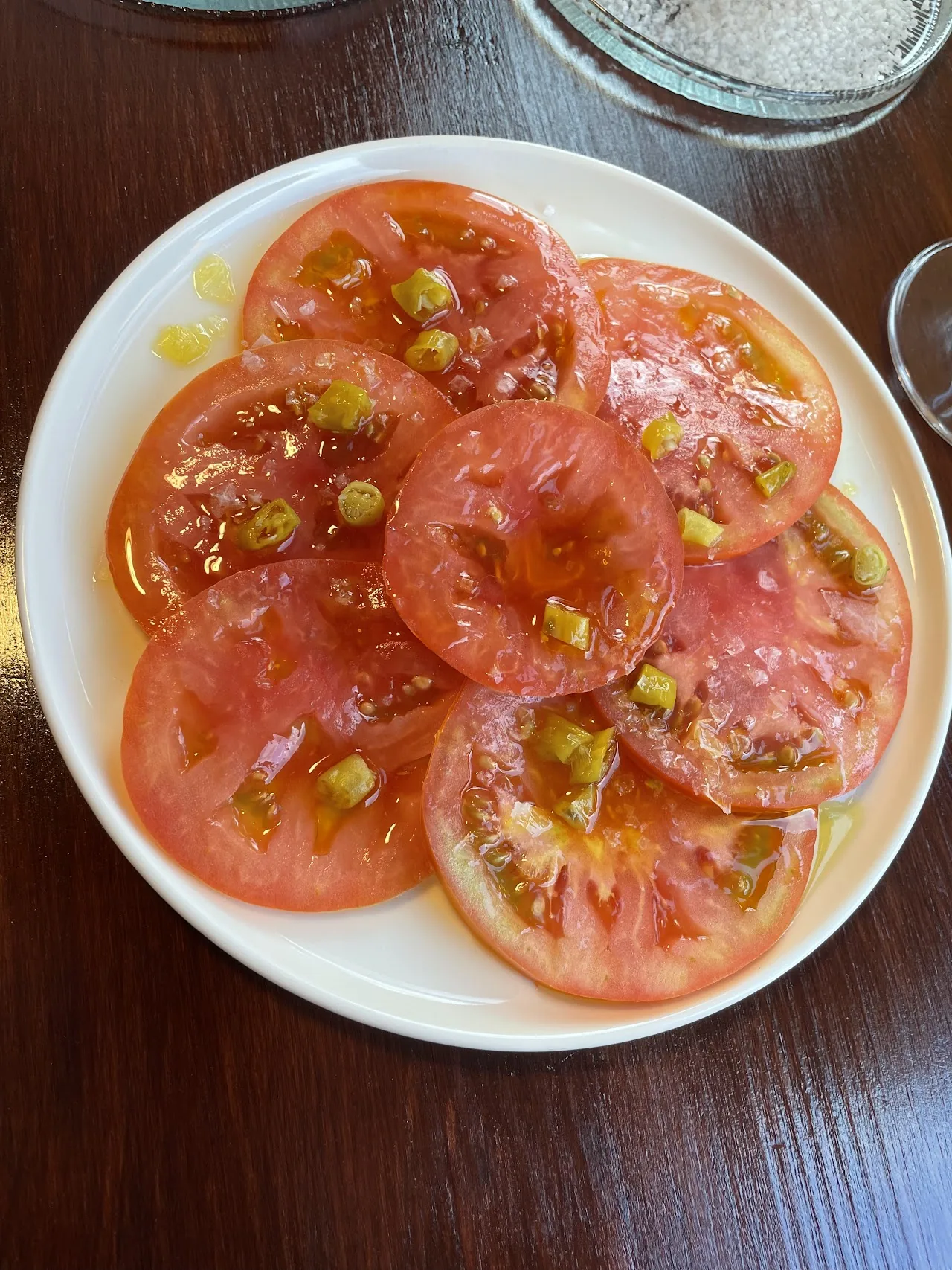Sliced tomato salad with capers on a white plate