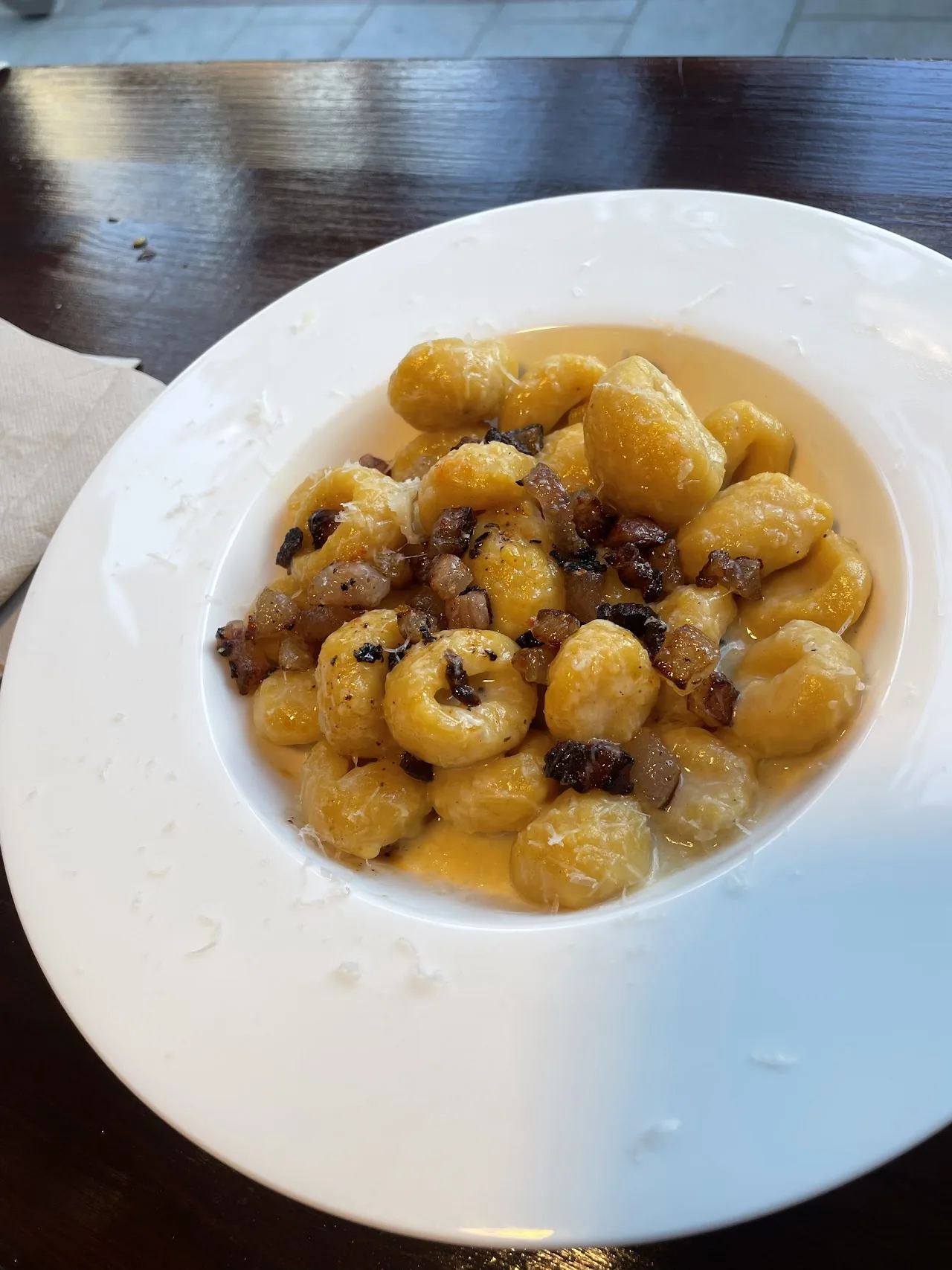 A plate of small round dumplings in a creamy sauce with dark garnish