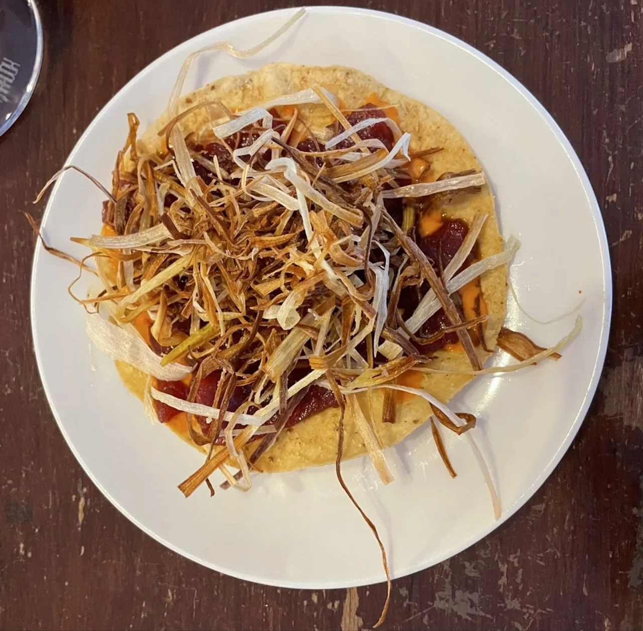 A tortilla topped with shredded meat and sauce