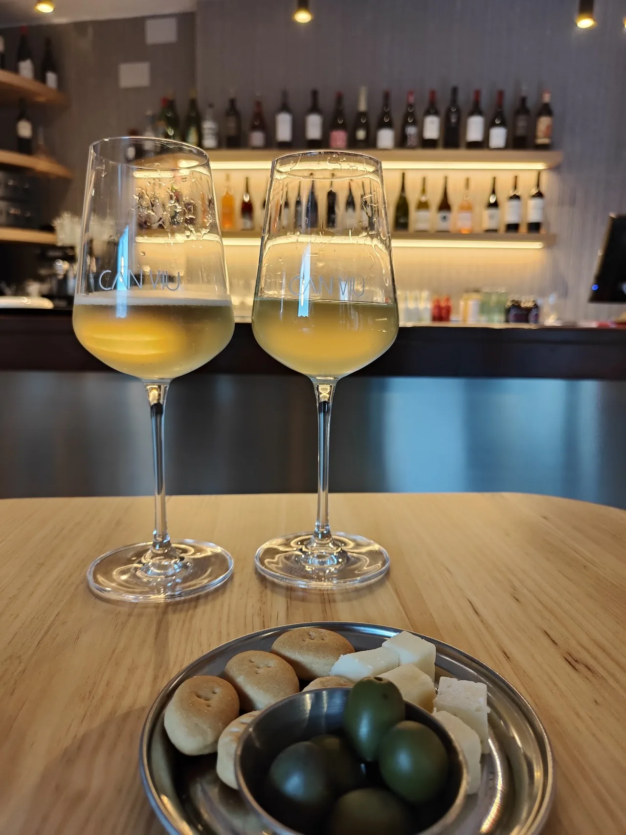 Two glasses of white wine beside a bowl of olives