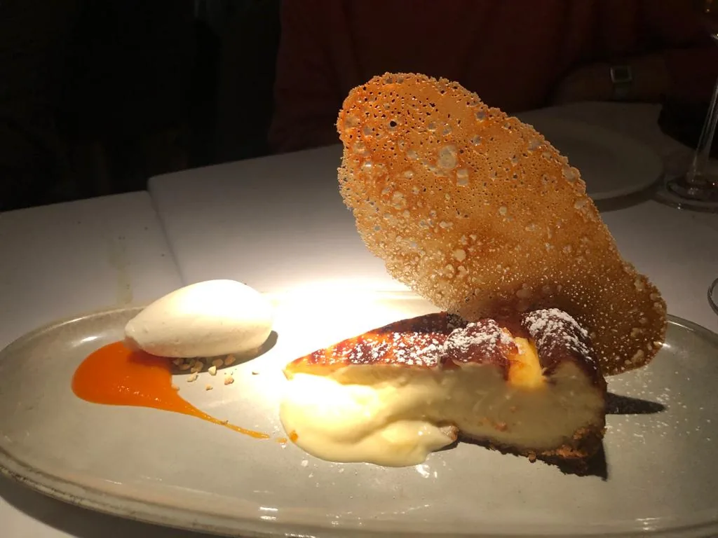 A dessert plate with a cream quenelle and a crisp tuile