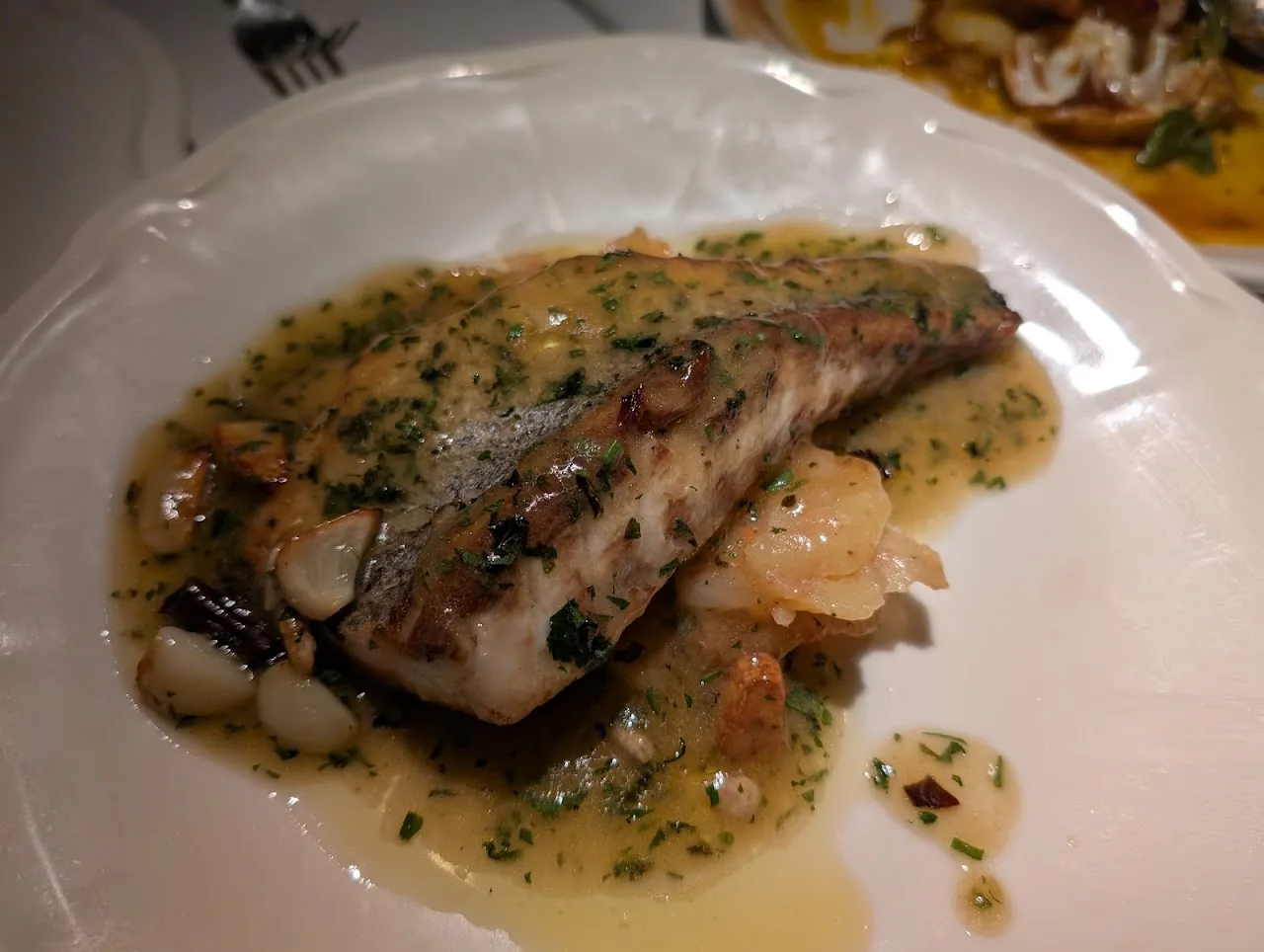 A fish fillet in a butter and parsley sauce