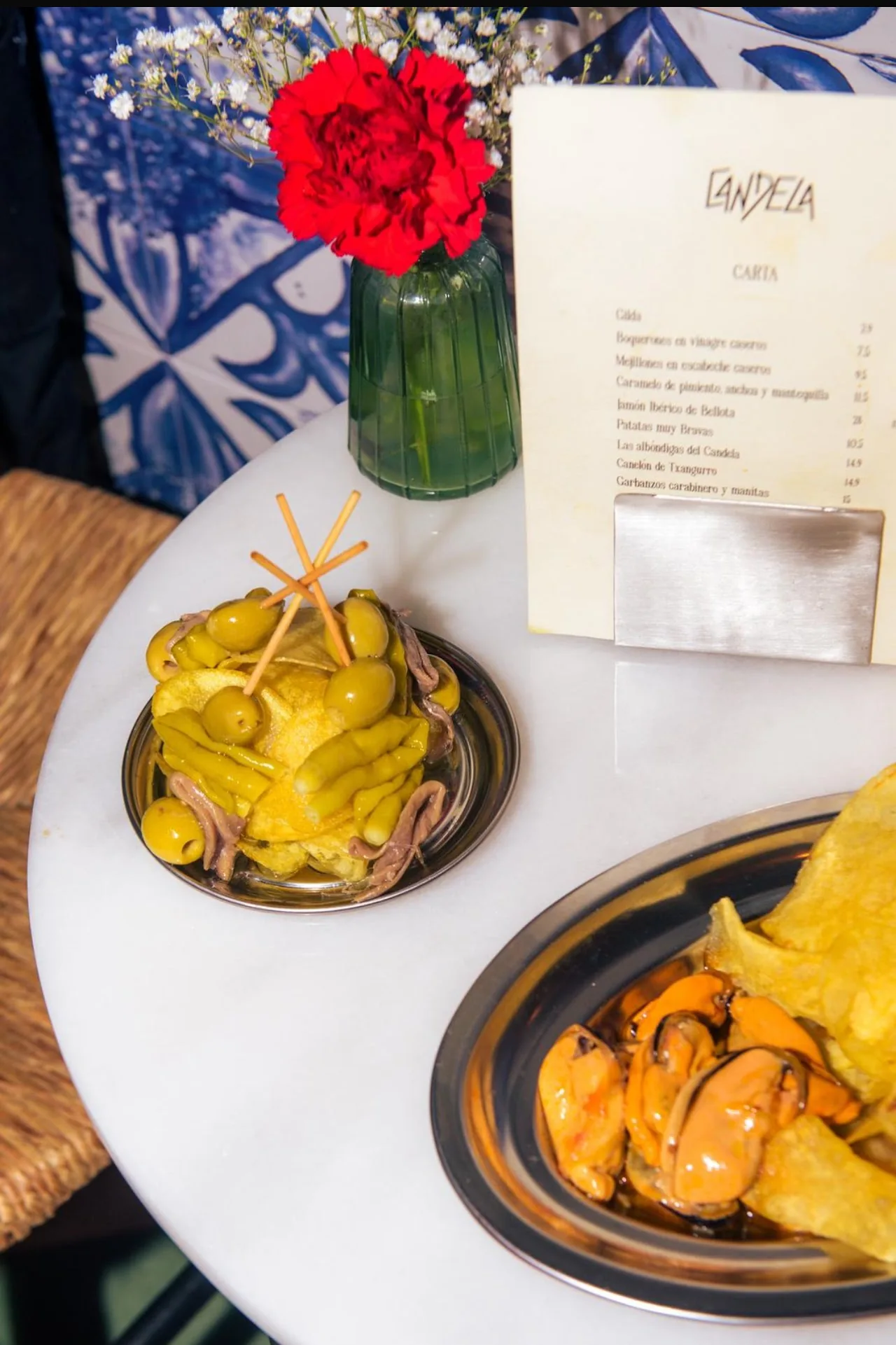 A table with a plate of fried pastries and a plate of marinated peppers, seen from above