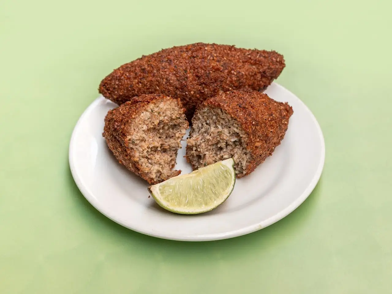 Breaded meat cutlets with a lime wedge on a white plate, at Cantinho Brasileiro.