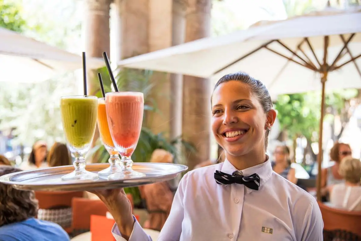 A waitress carrying a tray of fresh juices on the terrace