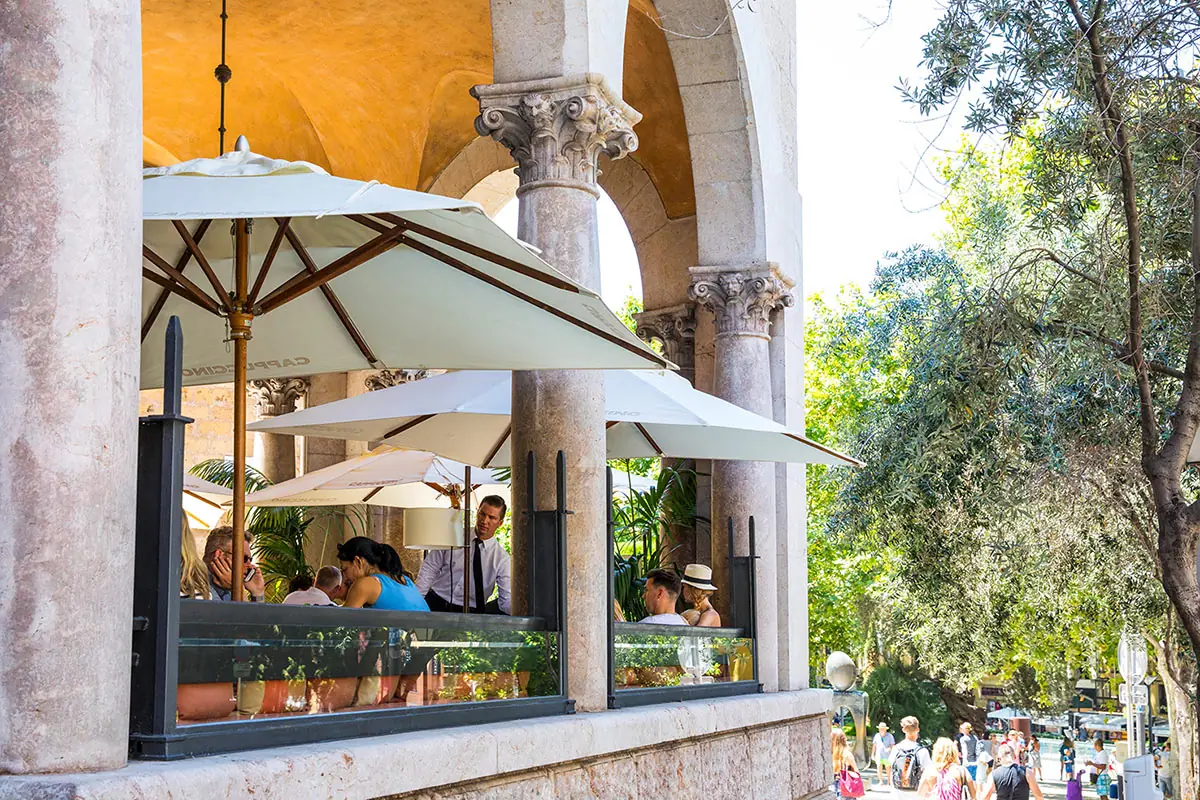 White parasols over the terrace beneath the stone arches