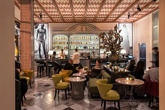 The bar room with yellow armchairs and marble floor inside Hotel Cappuccino