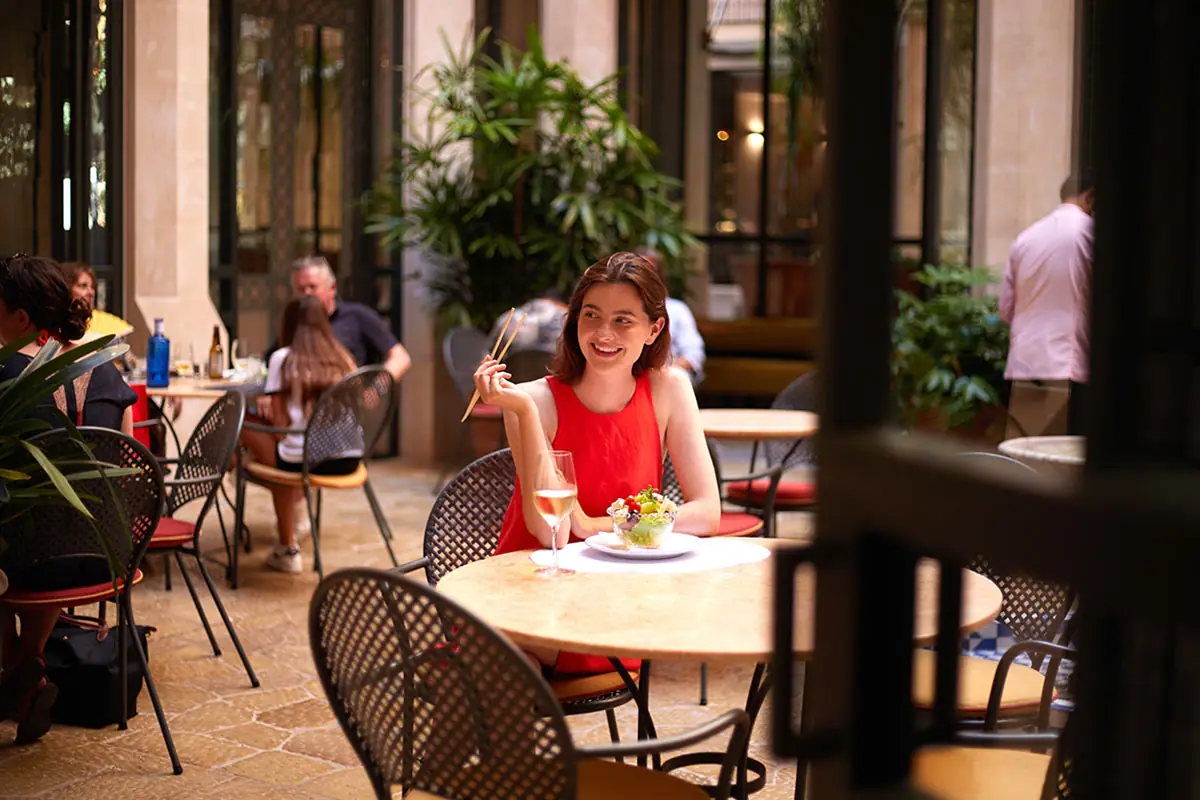 A guest at a terrace table with a plate and a glass of wine