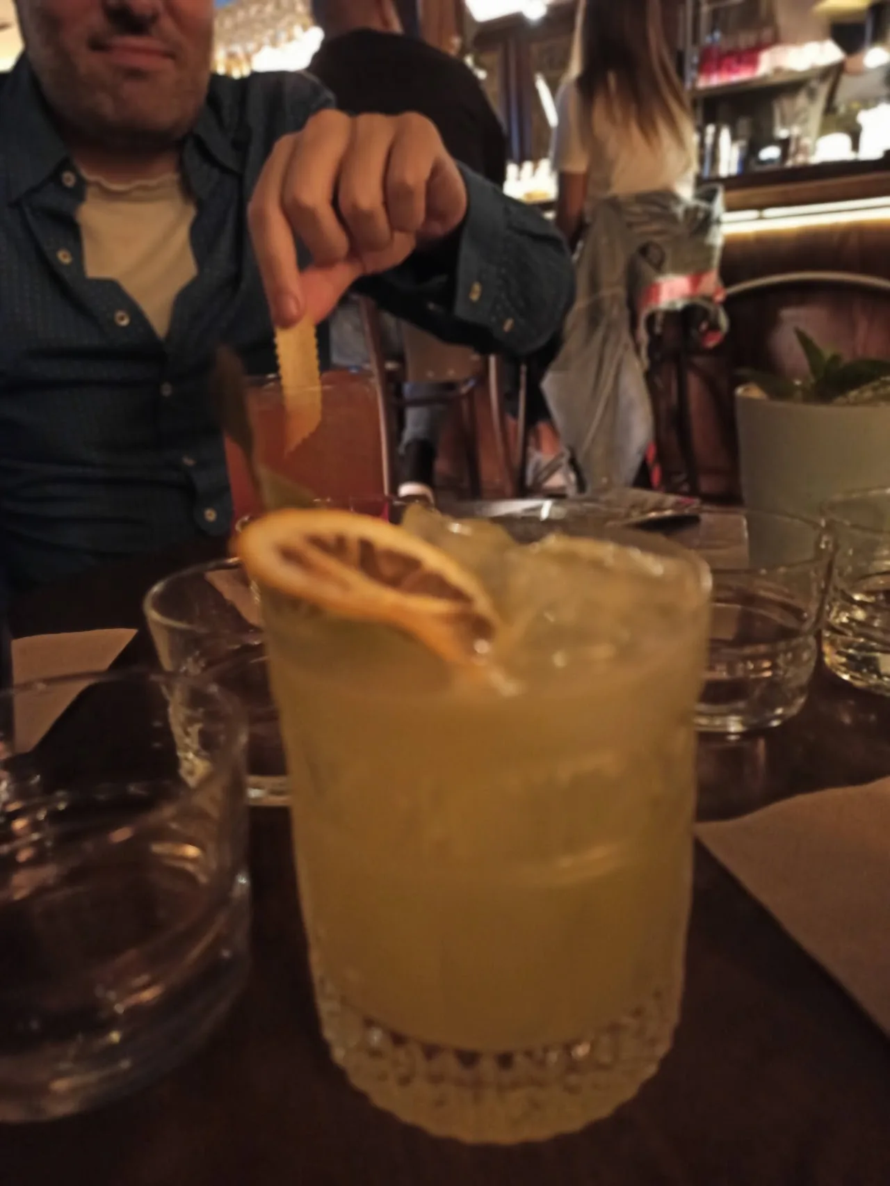 A hand holding a cocktail garnished with a lemon twist