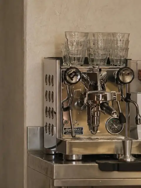 Chrome Rocket espresso machine on a steel bar counter with stacked cut-glass tumblers on top