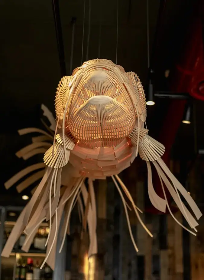 Large fish-shaped woven pendant light fixture hanging inside the restaurant