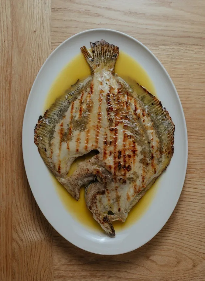 A grilled flatfish on an oval plate with olive oil