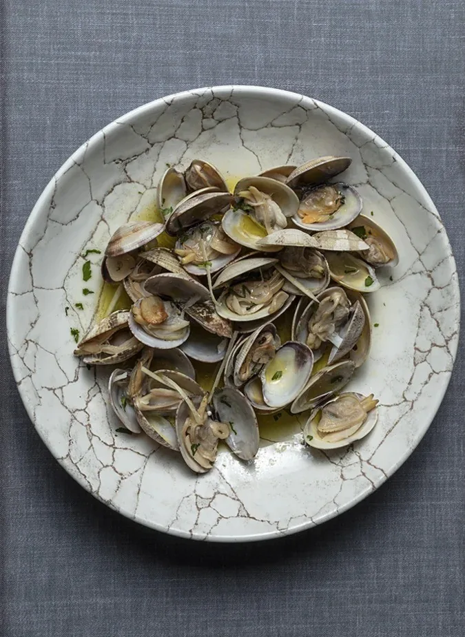 A round plate of clams in a light sauce