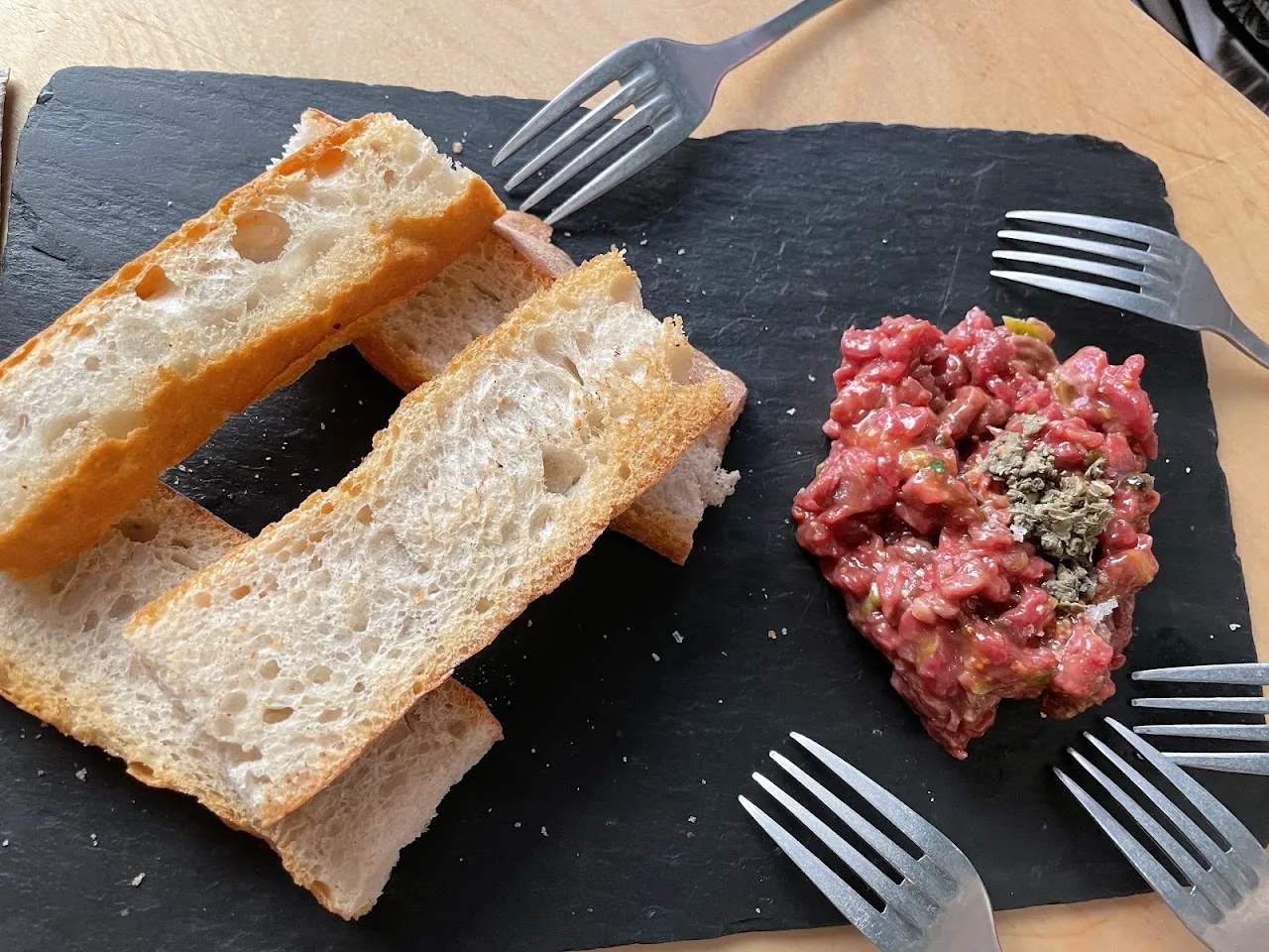 A slate board with bread and a portion of steak tartare