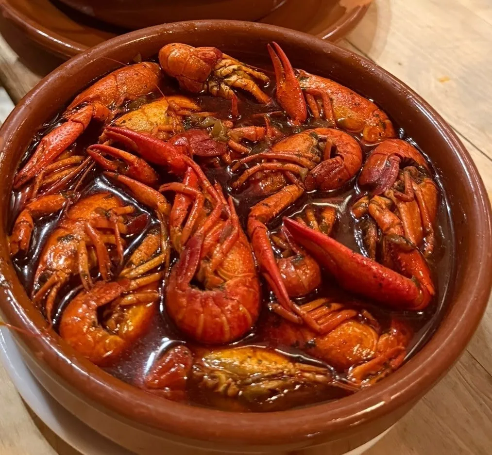 An earthenware dish of red cooked crayfish in sauce
