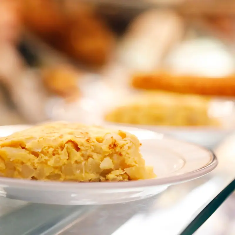 Close-up of a thick wedge of Spanish tortilla (potato omelette) on a white plate, at Casa Ángela