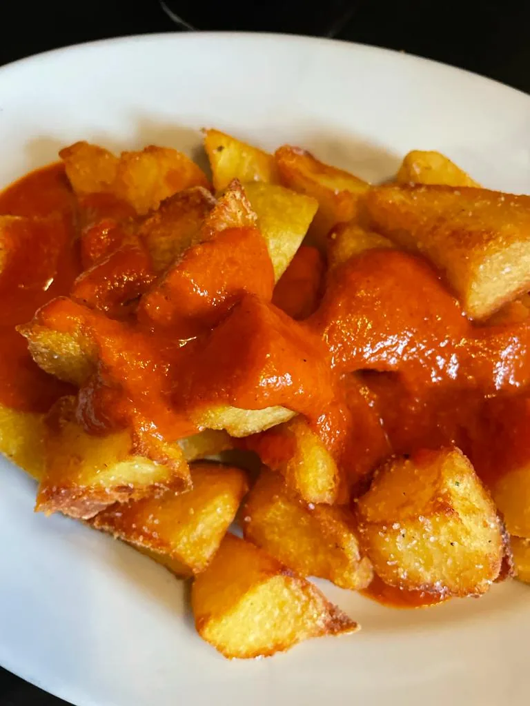 A plate of patatas bravas in spicy tomato sauce
