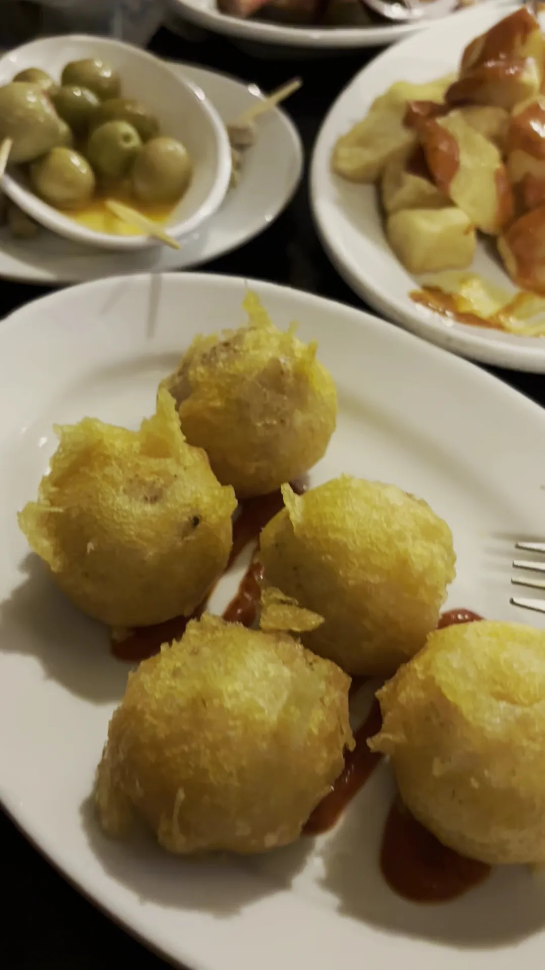 A plate of fried battered buñuelos with a dipping sauce