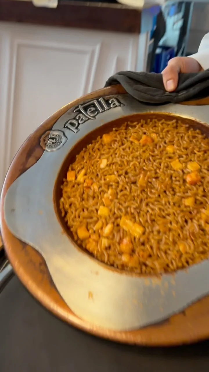 A paella dish of golden rice held at the table