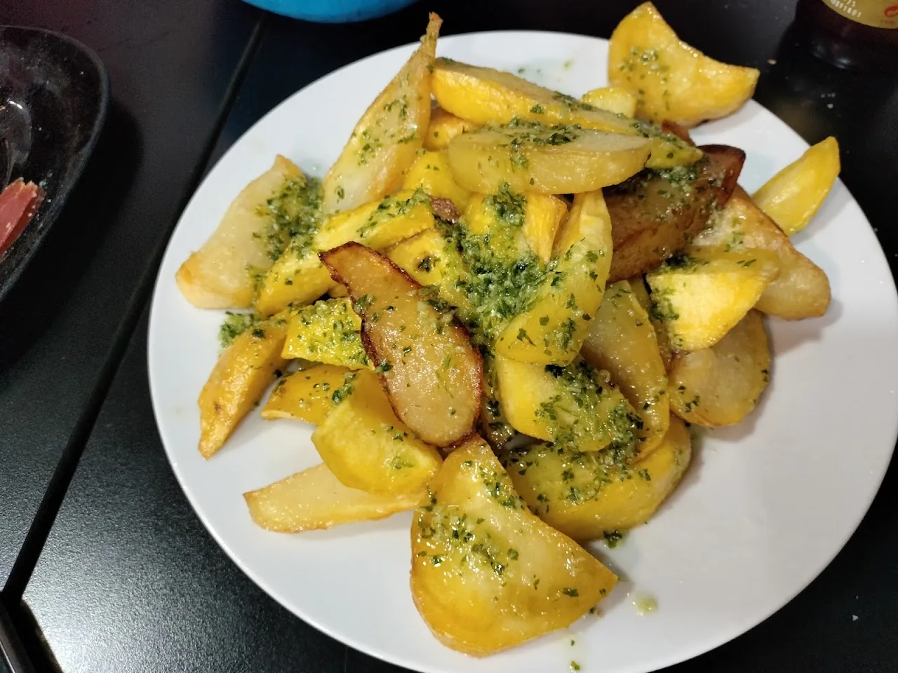 A plate of golden potato wedges with garlic and parsley