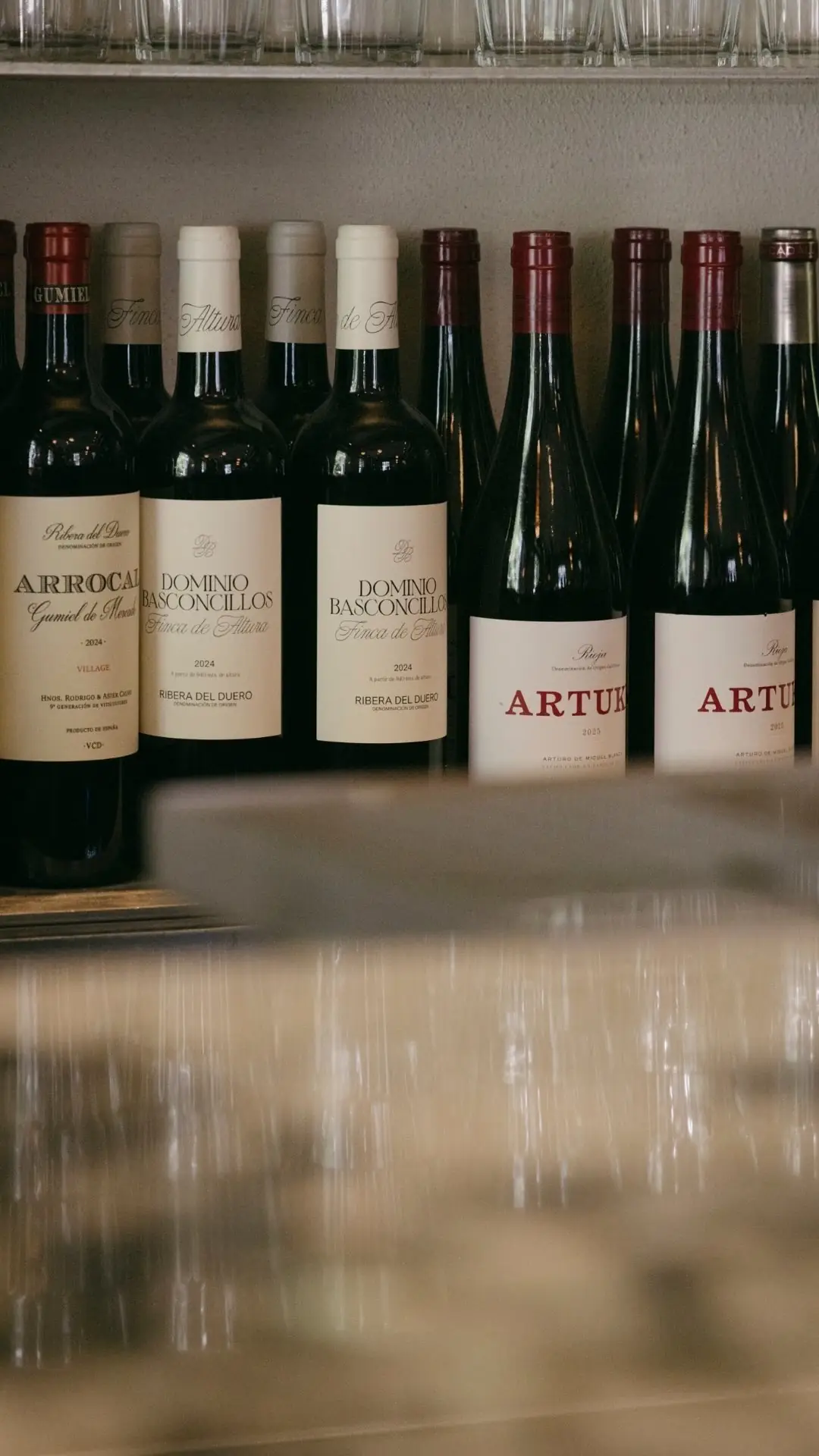 Rows of wine bottles with Ribera del Duero and Rioja labels on illuminated bar shelving
