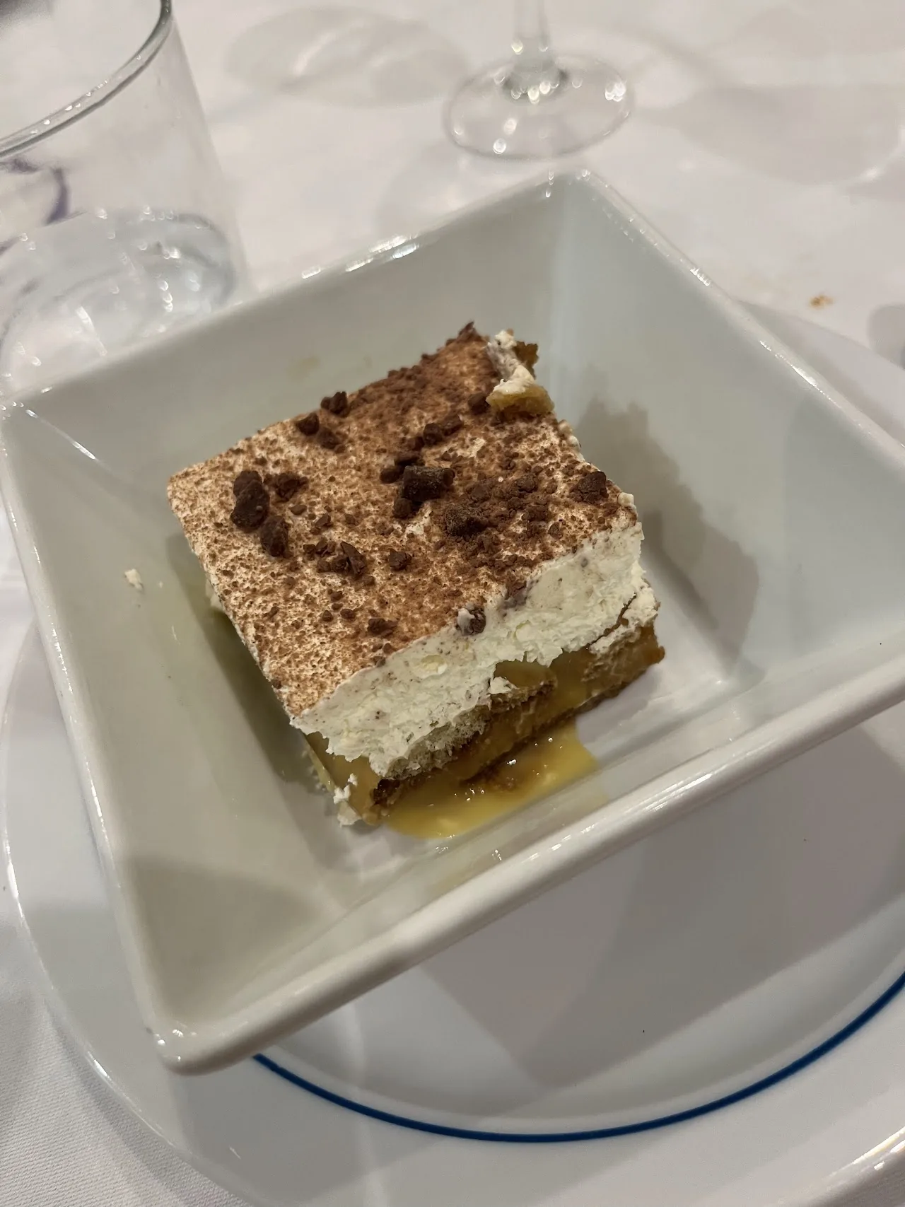 A square portion of tiramisu dusted with cocoa powder