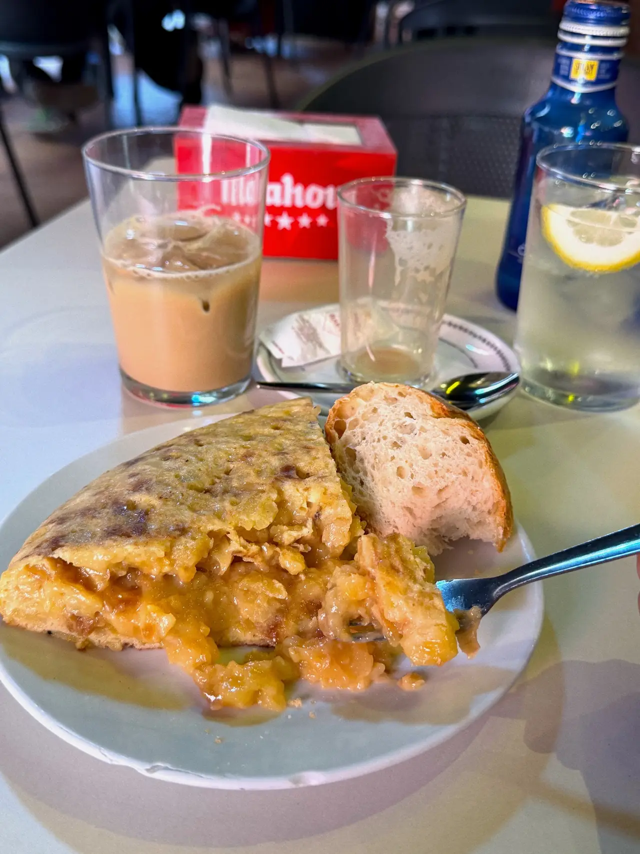 Wedge of runny Spanish tortilla de patata with bread, fork lifting a bite