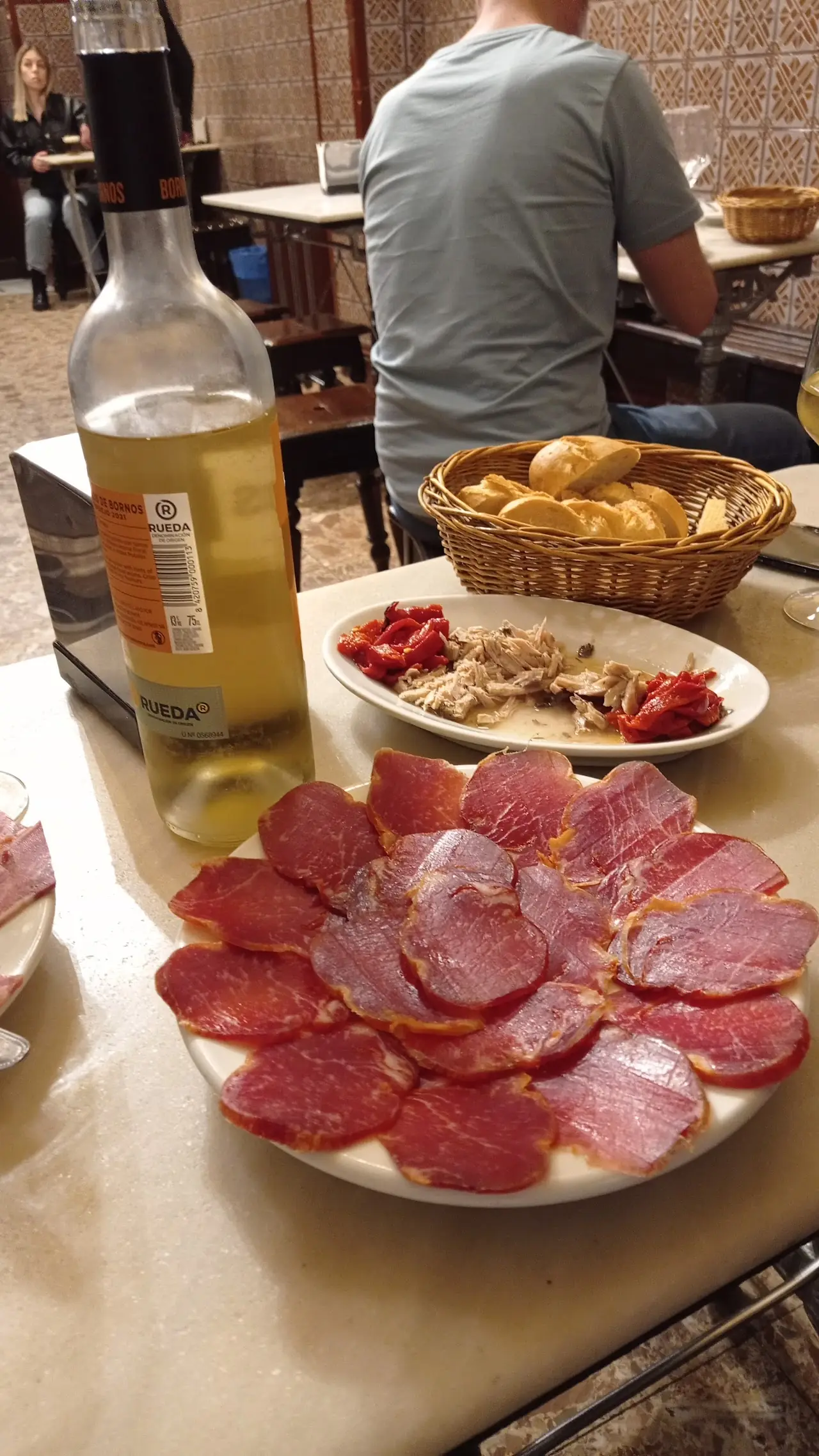 Sliced cured lomo and chorizo with a basket of bread.