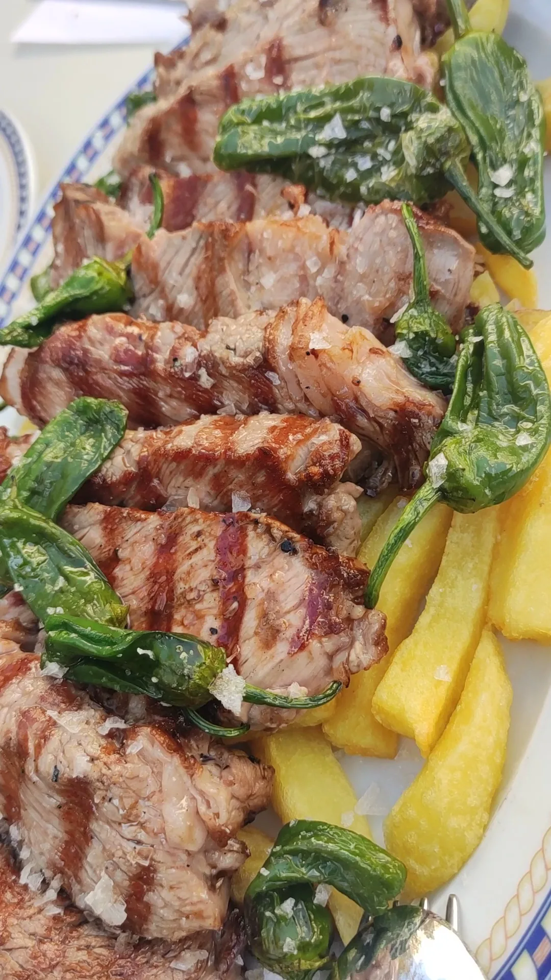 Grilled pork and green peppers on a blue-rimmed plate