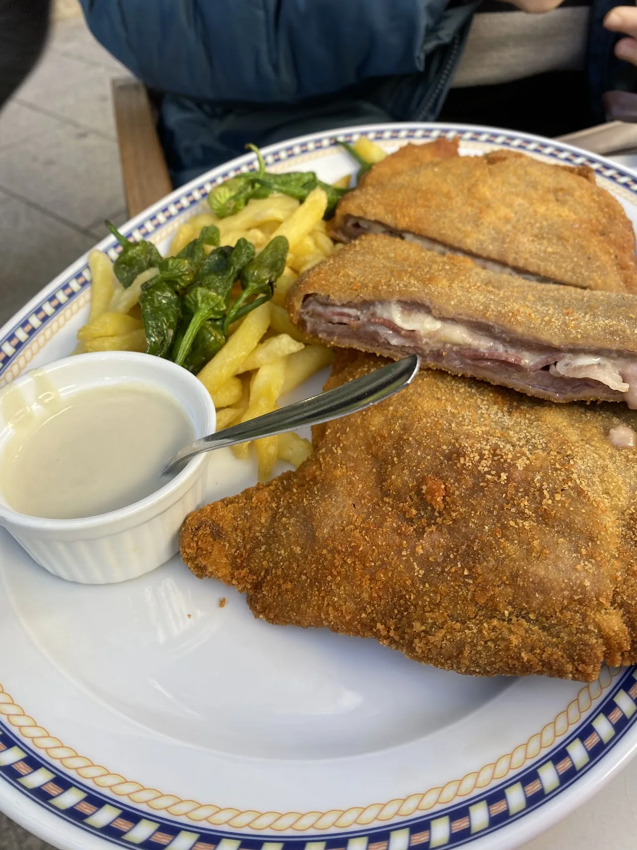 A breaded veal cutlet with french fries and a dipping sauce