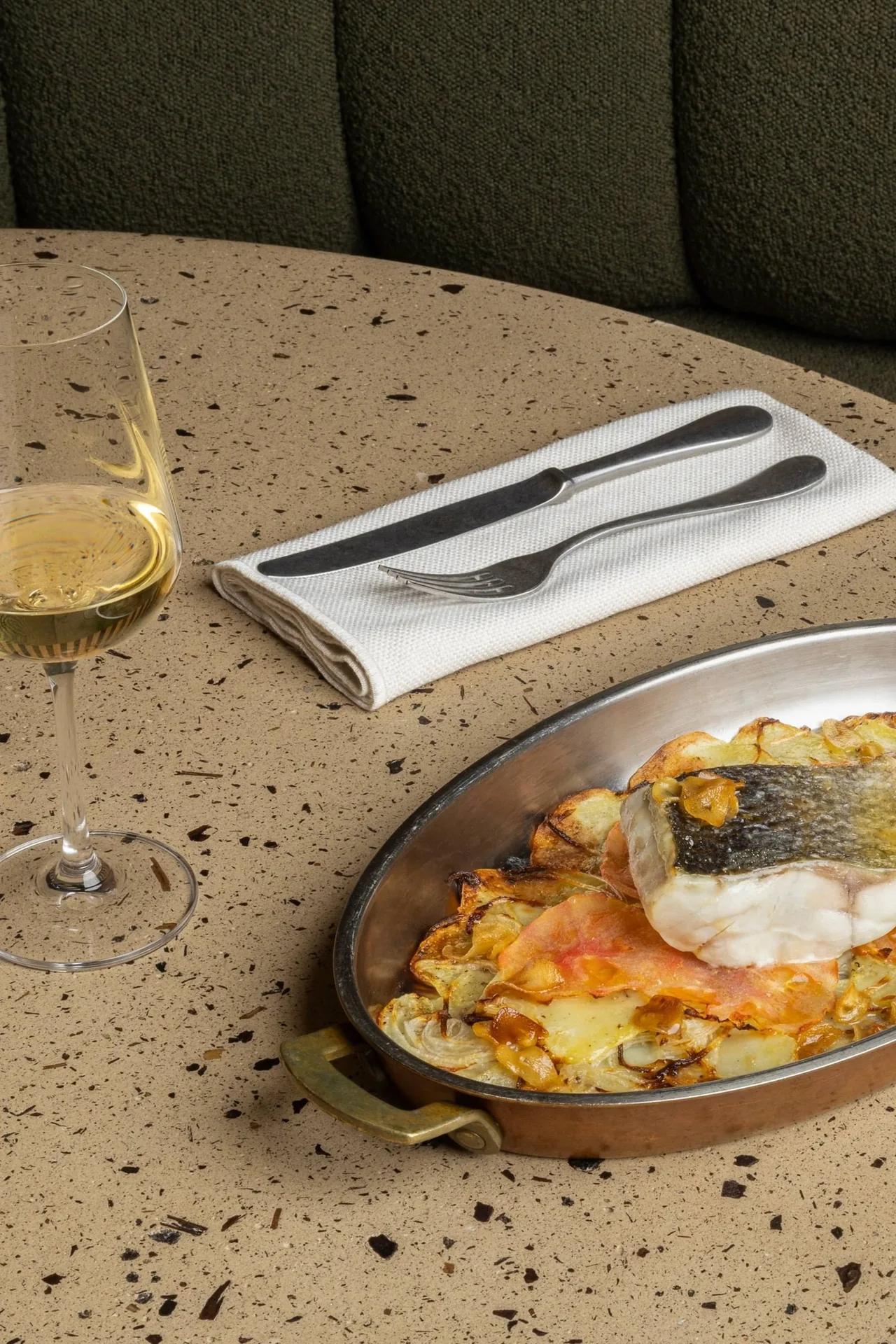 A fish dish with potatoes in an oval copper pan