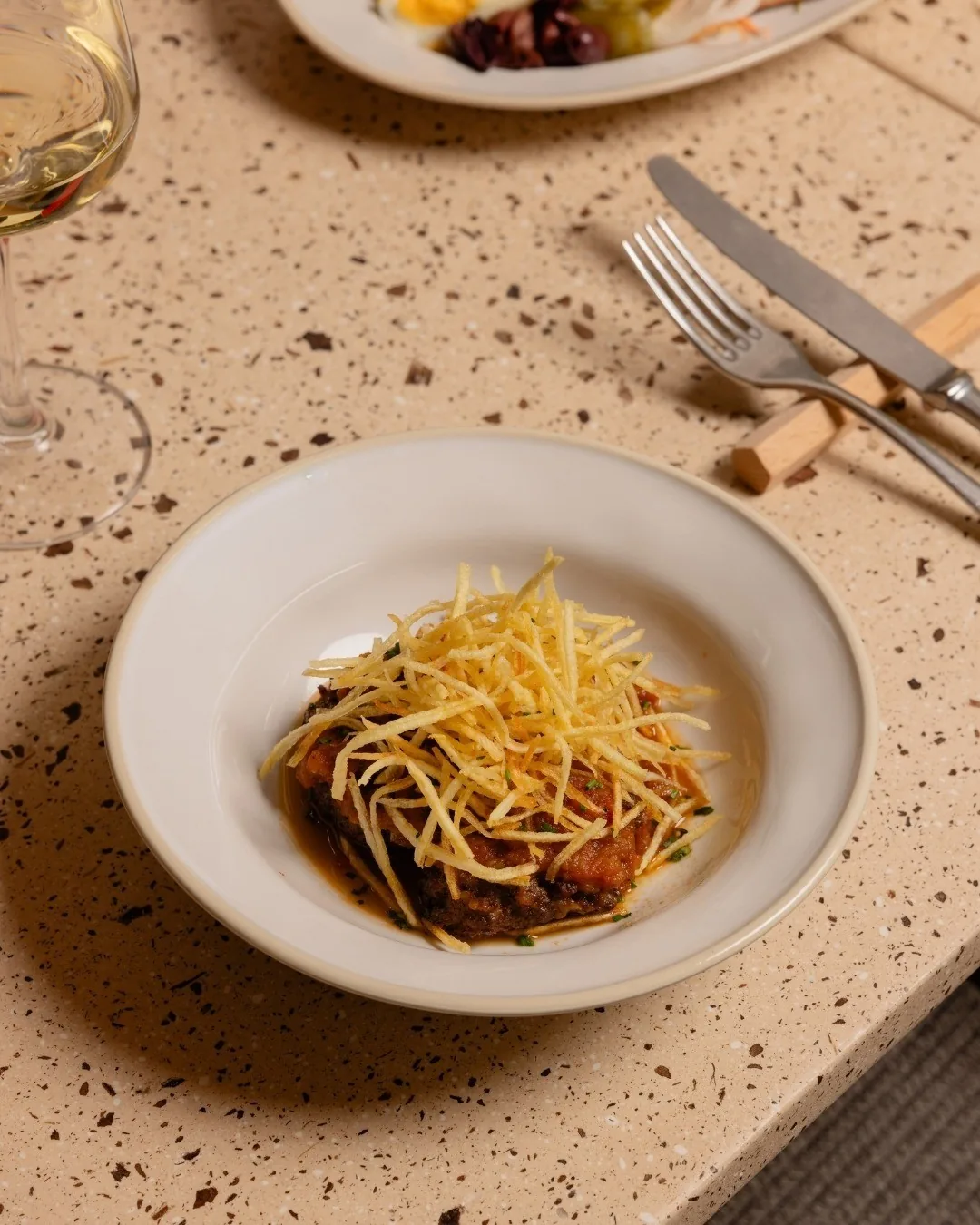A dish of thin strands over dark sauce in a white bowl