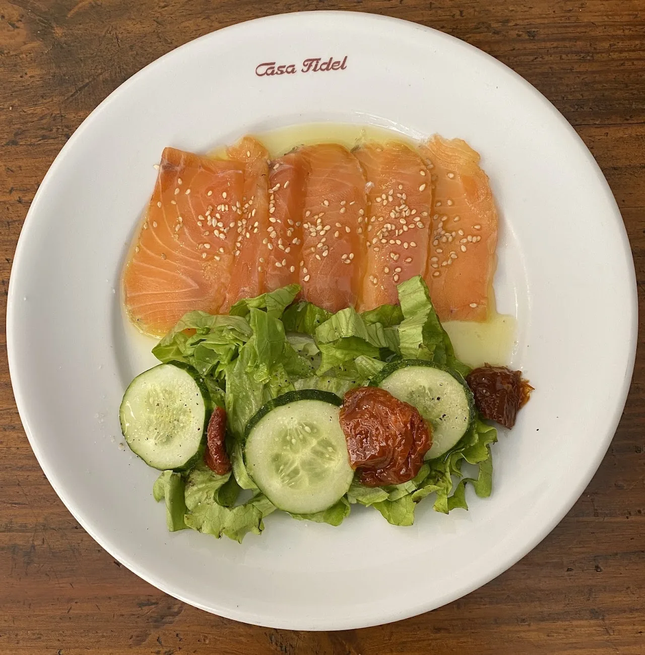 A plate of smoked salmon with lettuce, cucumber, and cherry tomato