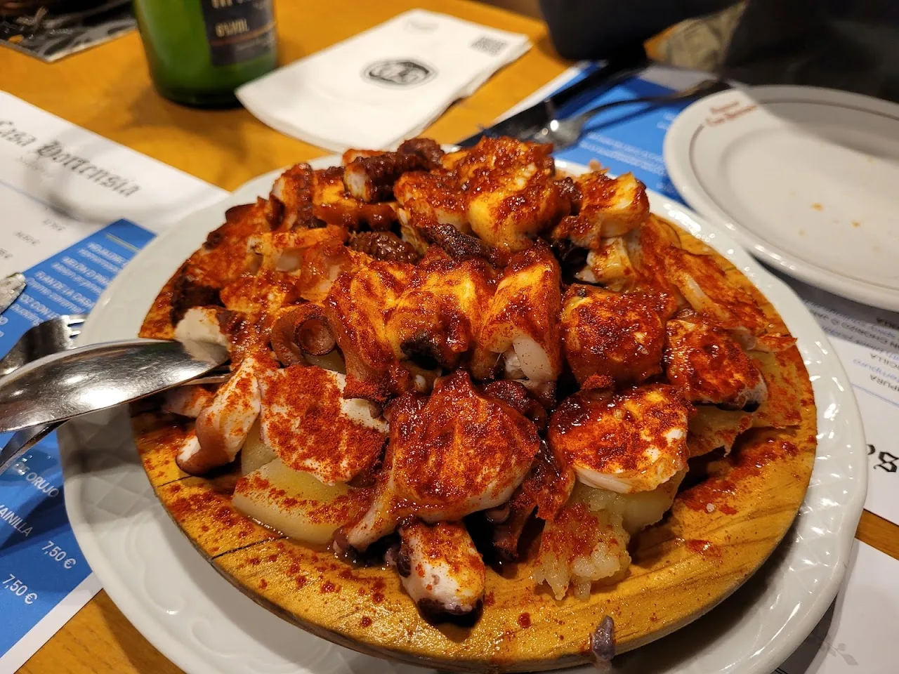 A plate of fried potato bites in spicy red sauce
