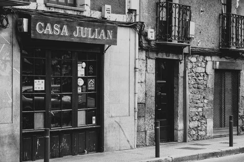 Black-and-white exterior of a Casa Julian storefront with wooden sign, large glass window and stone facade
