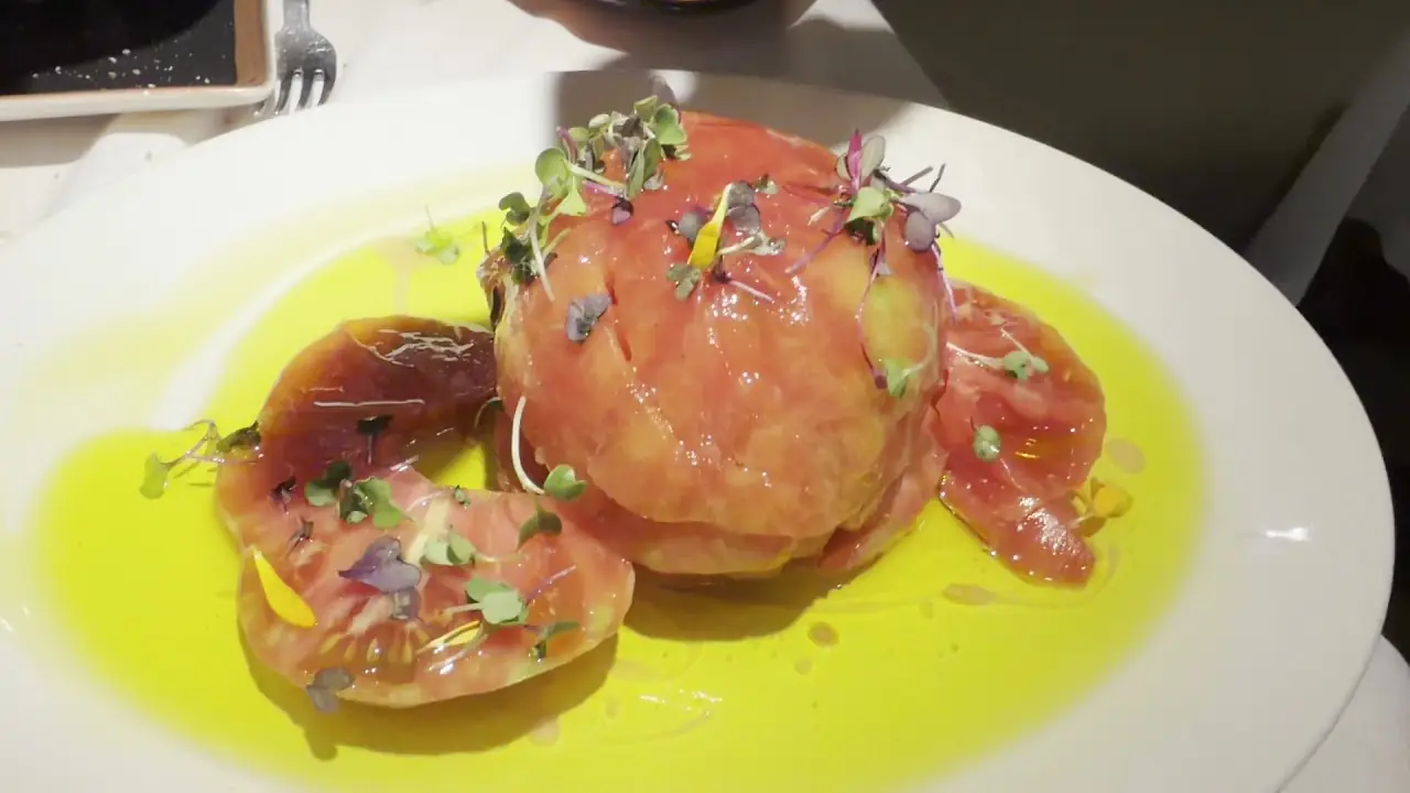 A tomato and burrata parcel drizzled with olive oil, garnished with edible flowers.