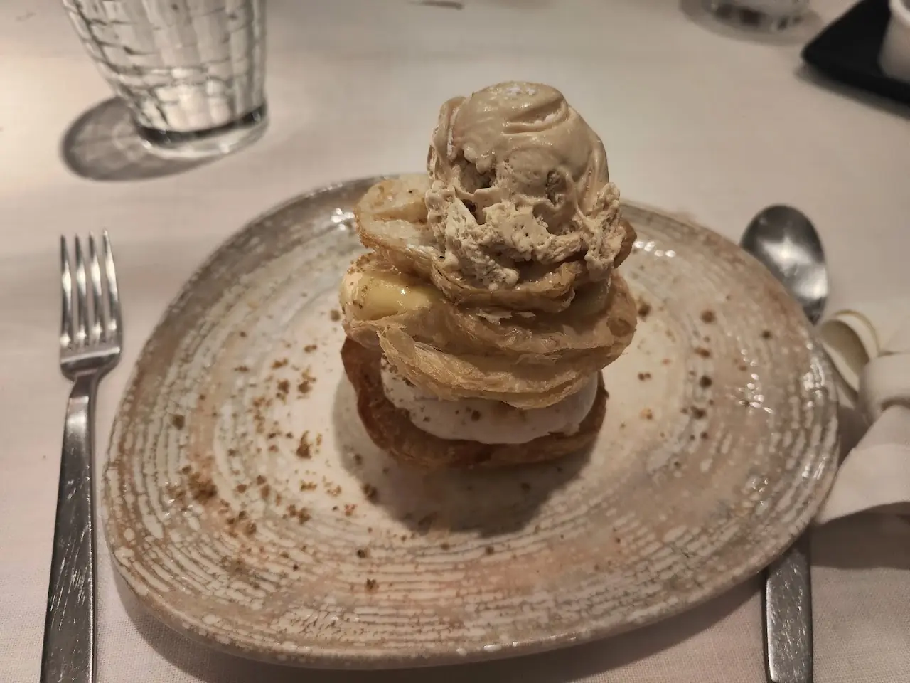 A stacked dessert of thin pastry rounds topped with a scoop of ice cream.