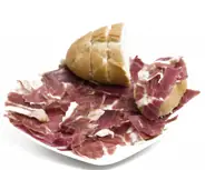 Plate of sliced cured meat with a bread roll on a white background