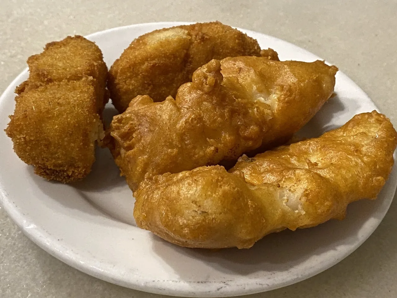 Golden battered fried pieces on a white plate