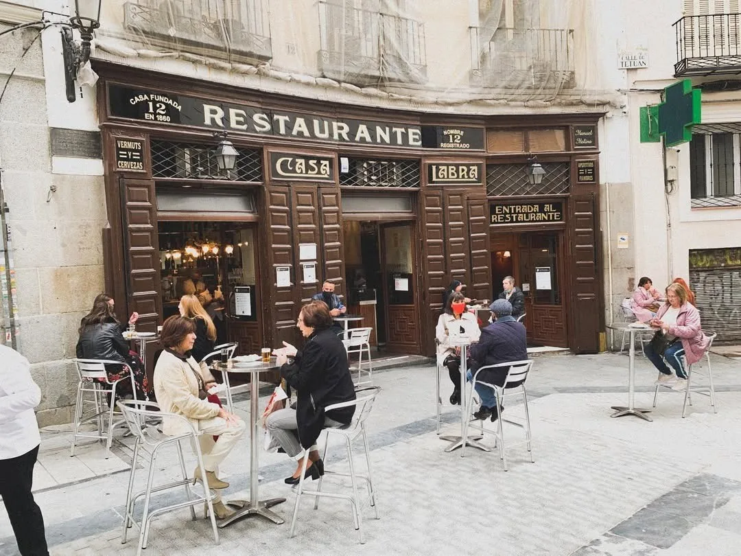 The wooden facade of a restaurant with tables and diners on the street terrace