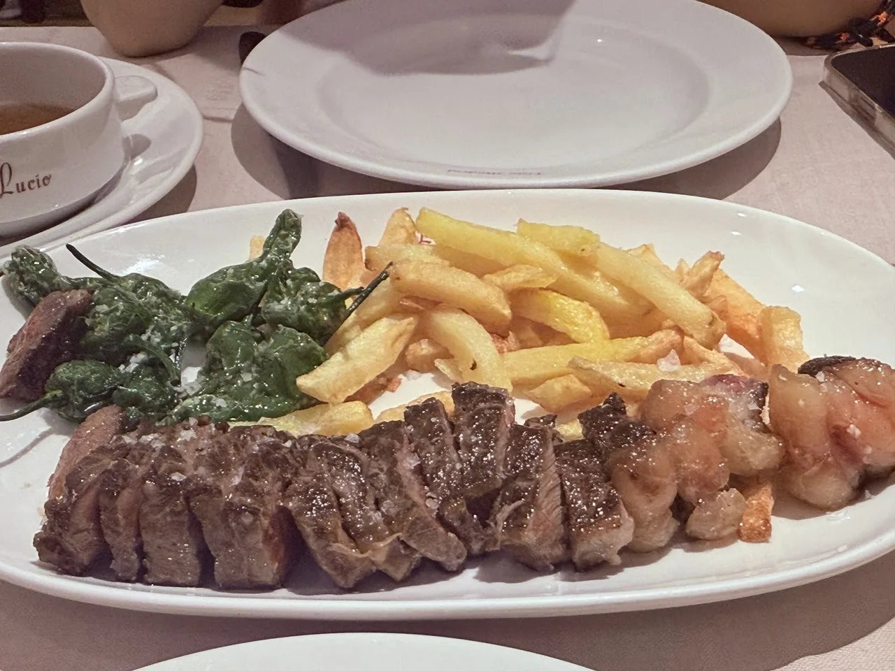 A grilled steak with fries and green peppers on a white plate