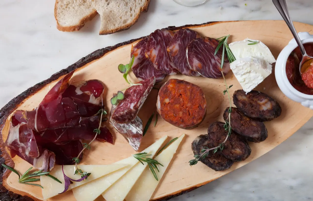 Close-up charcuterie board with cecina, salchichon, chorizo, morcilla, wedges of cheese and bread
