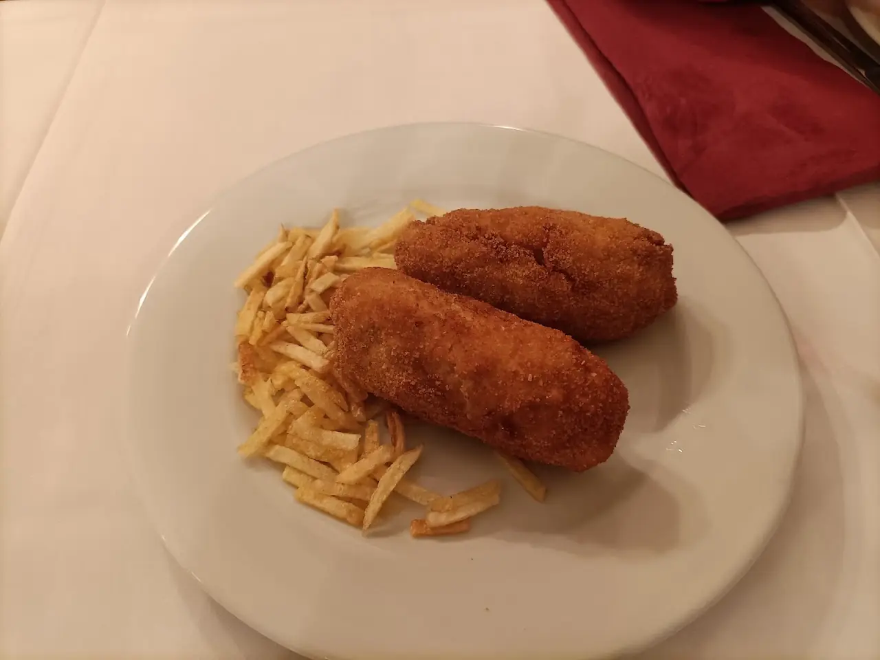 Two large croquetas with thin chips on a white plate
