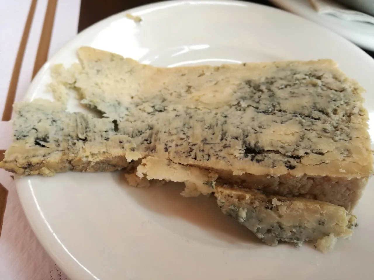 A wedge of blue cheese on a white plate