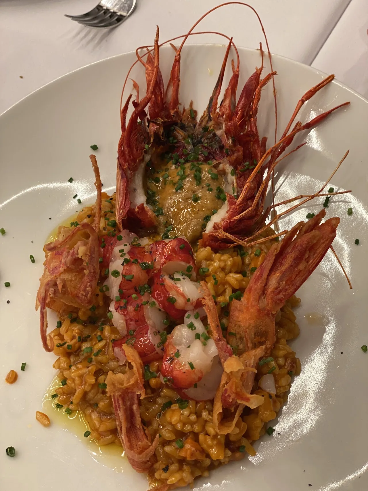 A rice dish topped with whole langoustines and herbs