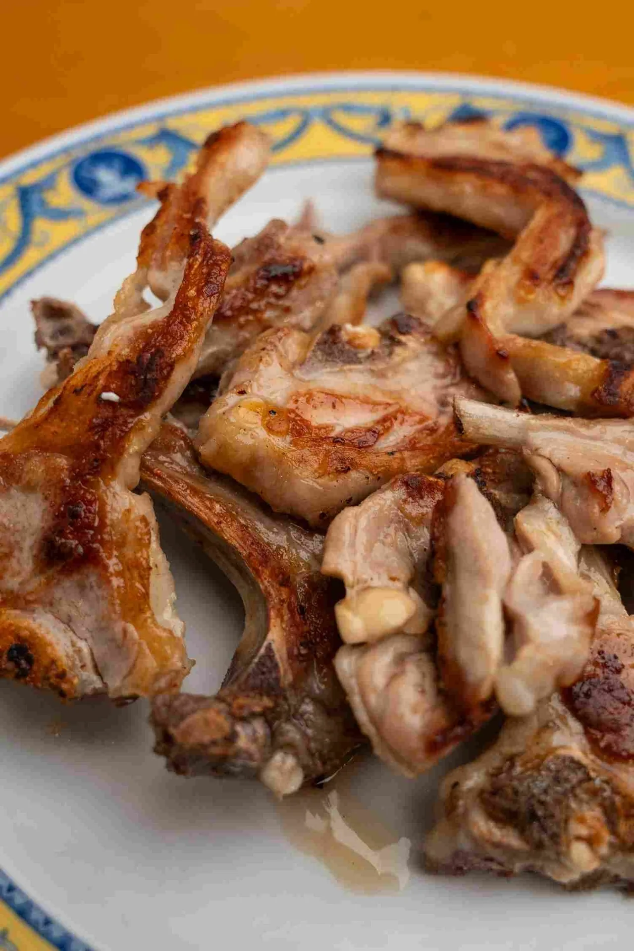 A plate of roasted lamb pieces on a blue-and-yellow patterned plate
